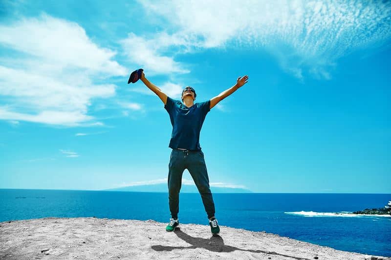 happy stylish man casual clothes standing cliff mountain