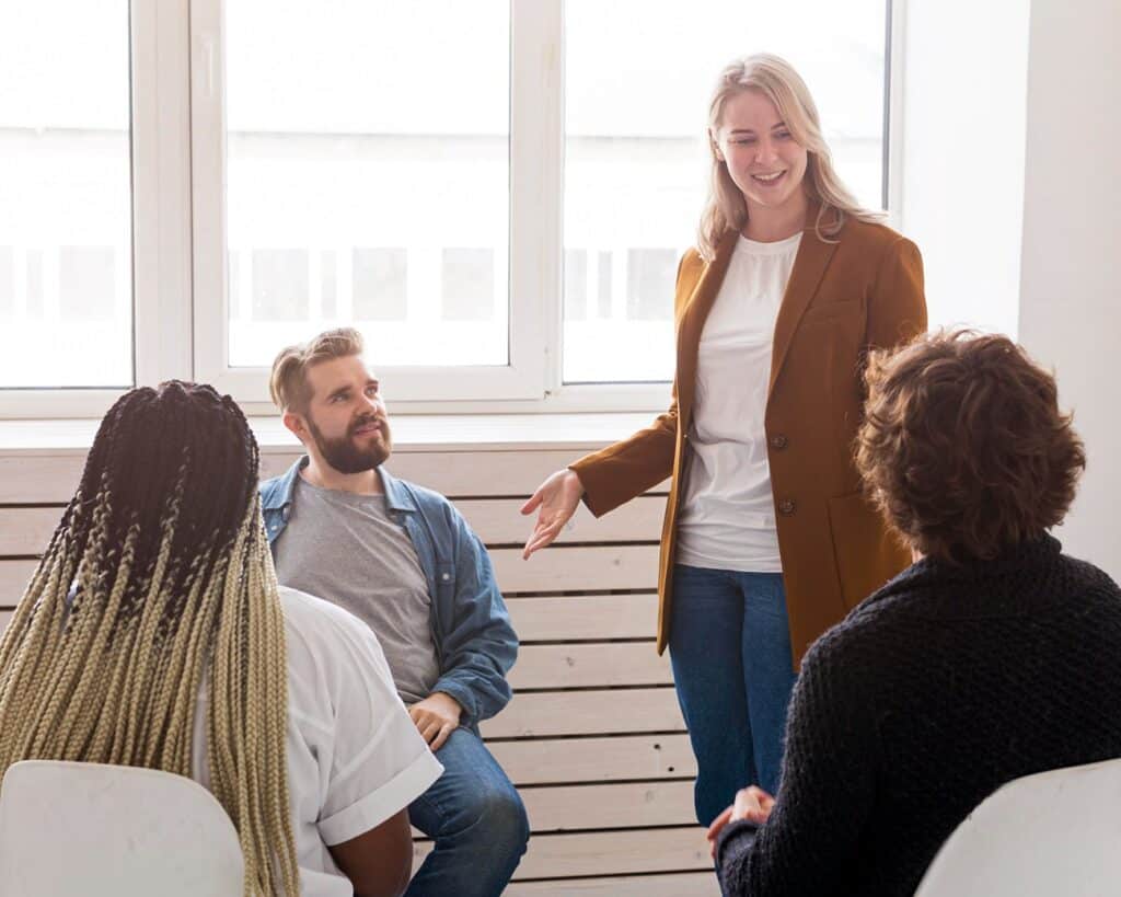 Group therapy session with diverse people. Woman leads discussion in a support group. Mental health and wellness concept.