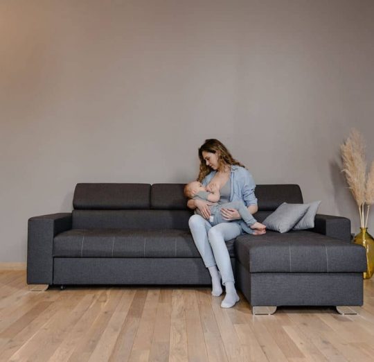 Postpartum Depression: Mother breastfeeding baby on couch, symbolizing maternal mental health and the challenges of new motherhood.